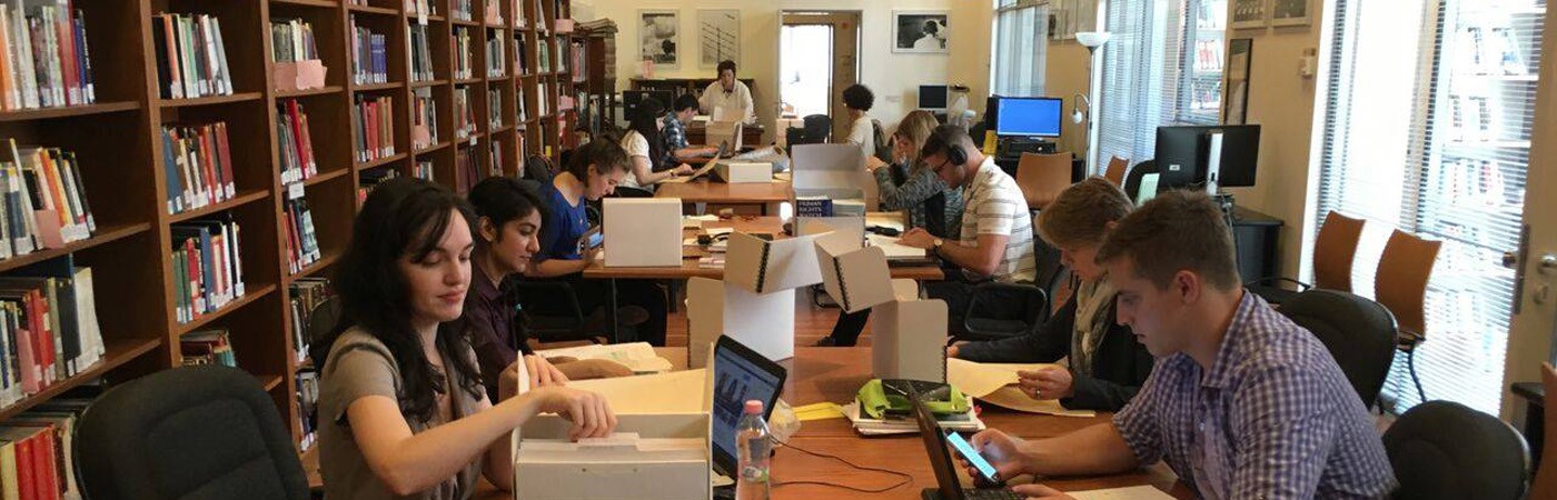 Graduate students read through archived files in a library
